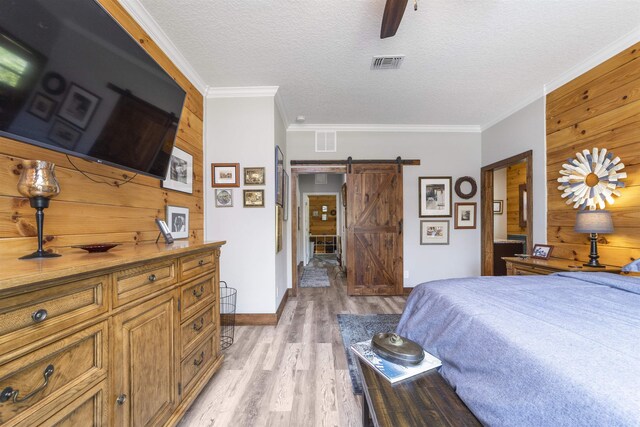 10635 Beckenger Ave, Hastings, FL 32145 - bedroom featuring crown molding, a barn door, wood walls, visible vents, and light wood-style floors