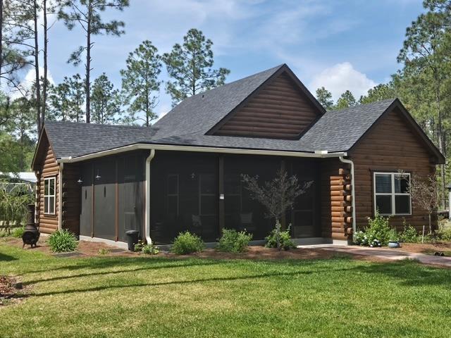 10635 Beckenger Ave, Hastings, FL 32145 - back of house with a sunroom, roof with shingles, log siding, entry steps, and a lawn