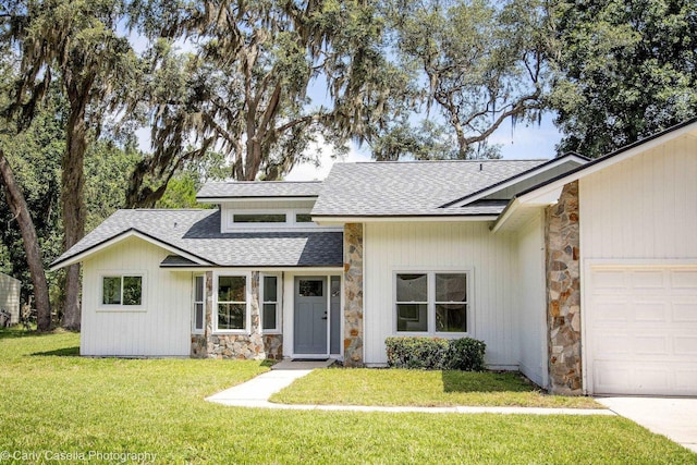 552 Fox Hollow Ln, Saint Augustine, FL 32086 - view of front facade featuring stone siding, roof with shingles, a front yard, and an attached garage