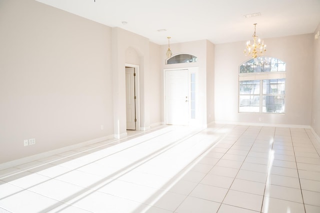 spare room with light tile patterned floors and a chandelier