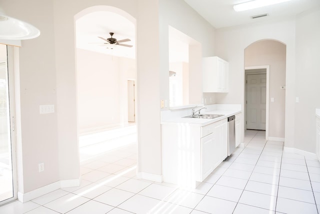 kitchen with light tile patterned floors, stainless steel dishwasher, sink, and white cabinets