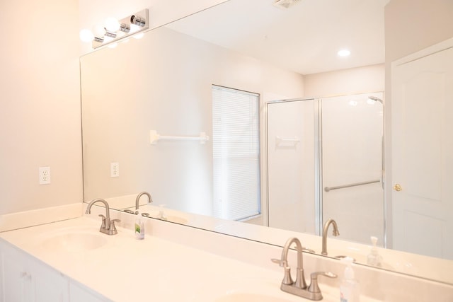 bathroom featuring a shower with door and vanity