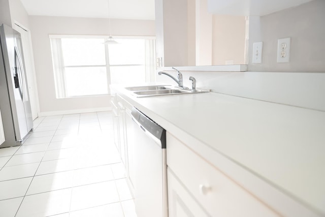 kitchen featuring sink, white cabinetry, light tile patterned floors, appliances with stainless steel finishes, and pendant lighting