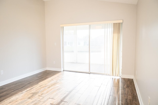 unfurnished room with vaulted ceiling, a wealth of natural light, and light hardwood / wood-style floors