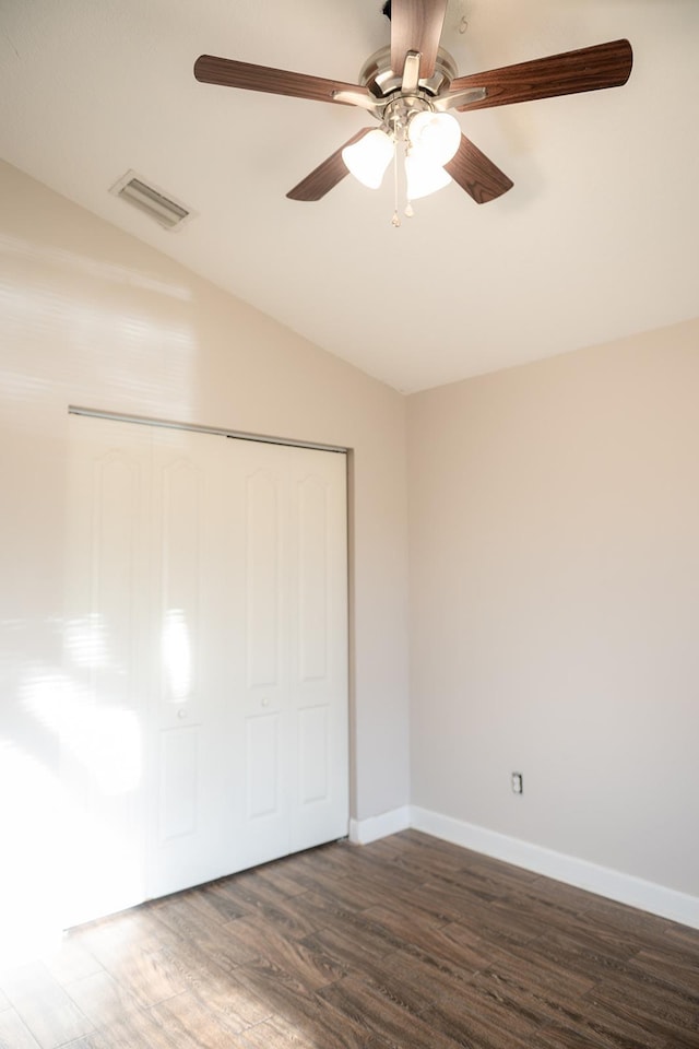 unfurnished bedroom featuring dark hardwood / wood-style flooring, vaulted ceiling, a closet, and ceiling fan