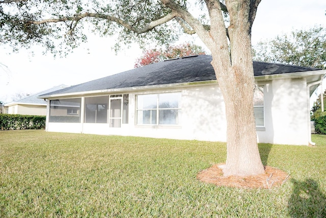 rear view of property with a lawn and a sunroom