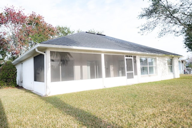 rear view of house featuring a sunroom and a lawn