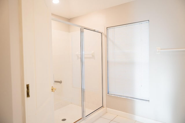 bathroom with a shower with door and tile patterned floors