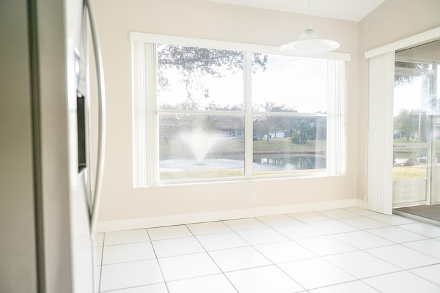 unfurnished dining area featuring a water view and light tile patterned floors