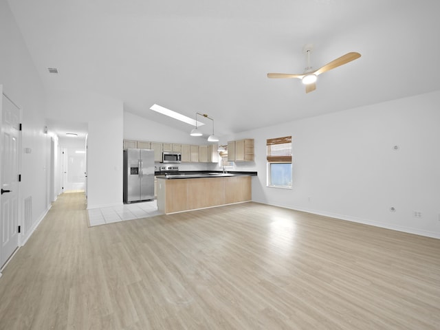 kitchen with vaulted ceiling with skylight, hanging light fixtures, light hardwood / wood-style floors, stainless steel appliances, and light brown cabinets