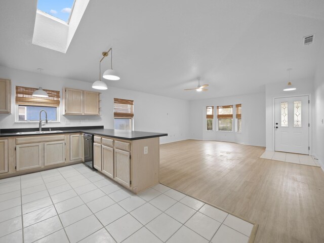 kitchen with a sink, dishwasher, dark countertops, a peninsula, and light brown cabinets