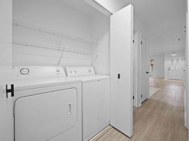 laundry area featuring washing machine and clothes dryer and light wood-type flooring