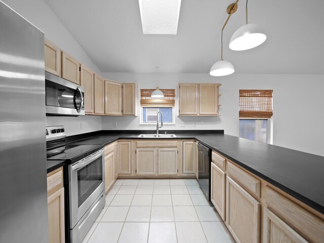 kitchen featuring appliances with stainless steel finishes, light brown cabinets, a sink, and dark countertops