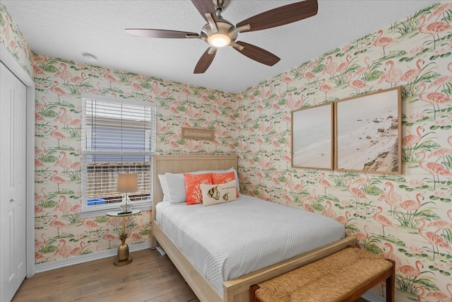 403 Second St, Saint Augustine, FL 32084 - bedroom featuring a closet, baseboards, a textured ceiling, wallpapered walls, and wood finished floors