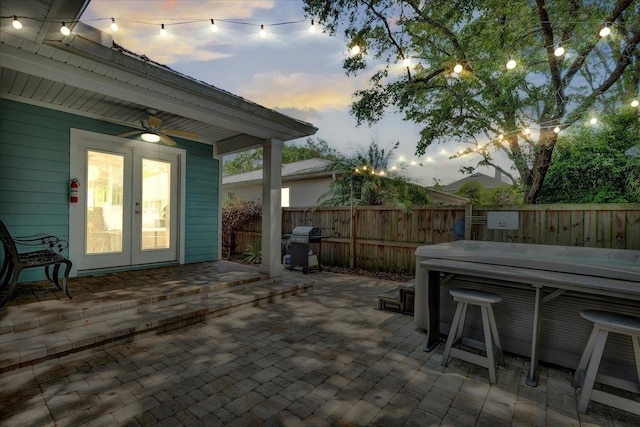 403 Second St, Saint Augustine, FL 32084 - patio terrace at dusk with a fenced backyard, a hot tub, area for grilling, french doors, and a ceiling fan