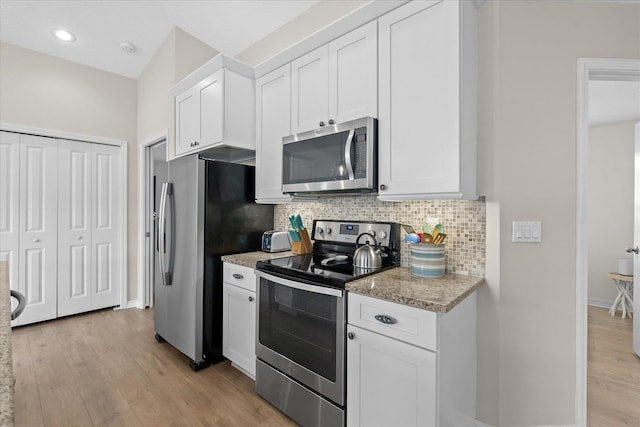 403 Second St, Saint Augustine, FL 32084 - kitchen featuring light wood-style flooring, backsplash, stainless steel appliances, and white cabinetry