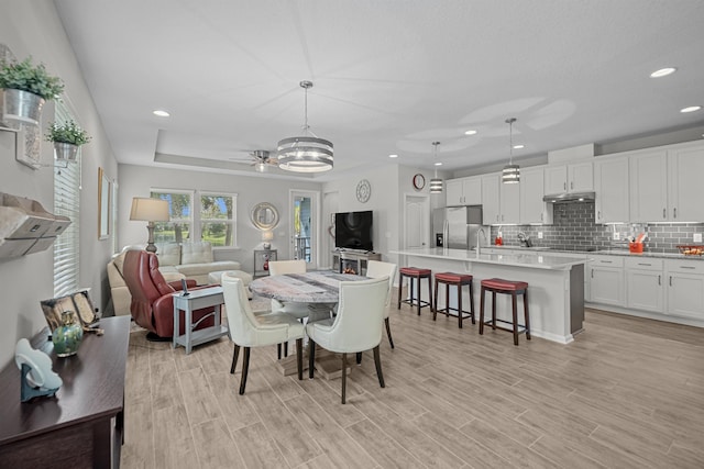 dining space featuring ceiling fan, light wood-type flooring, and sink