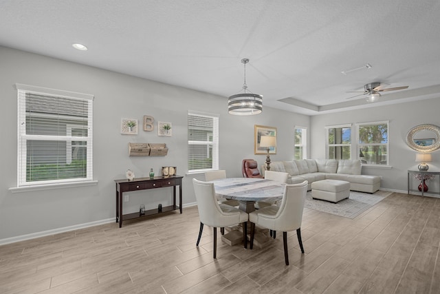 dining area featuring a textured ceiling, ceiling fan with notable chandelier, and light wood-type flooring