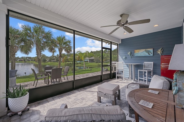 sunroom / solarium with ceiling fan and a water view