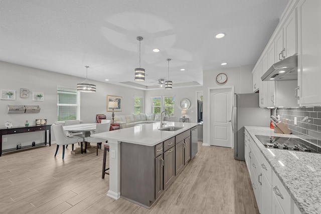 kitchen featuring a kitchen island with sink, sink, ceiling fan, light wood-type flooring, and white cabinetry