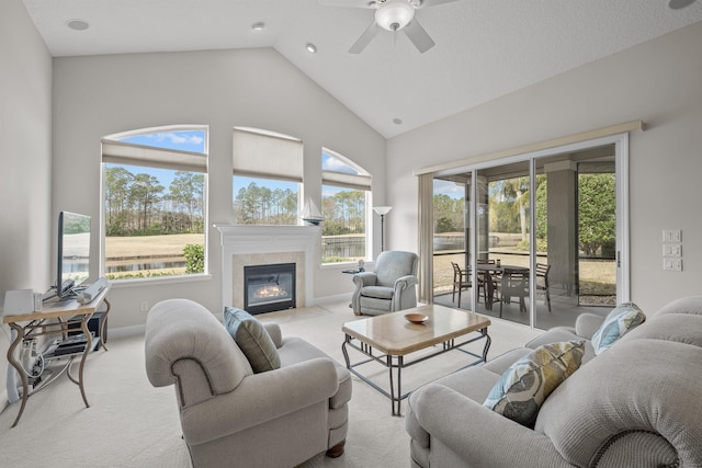 living room with a tile fireplace, vaulted ceiling, light carpet, and ceiling fan