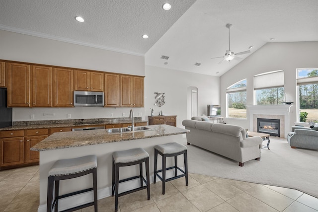 kitchen featuring dark stone countertops, sink, a breakfast bar, and a center island with sink