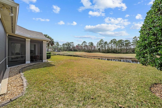 view of yard featuring a sunroom and a water view