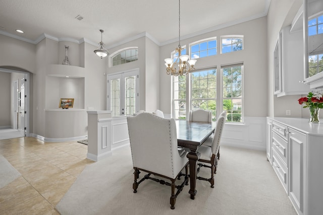 tiled dining space featuring crown molding, a high ceiling, french doors, and a notable chandelier