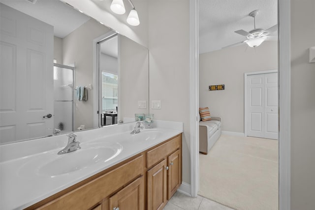 bathroom with a shower with door, ceiling fan, vanity, a textured ceiling, and tile patterned floors