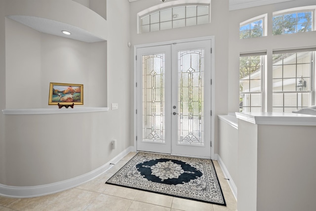 foyer entrance with tile patterned floors, french doors, and a high ceiling