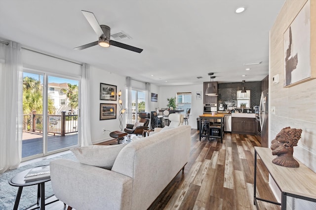 living room featuring tile walls, a wealth of natural light, ceiling fan, and dark hardwood / wood-style floors