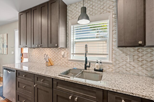 kitchen with sink, light stone counters, stainless steel dishwasher, backsplash, and pendant lighting