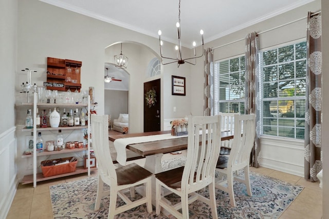 tiled dining area featuring crown molding and ceiling fan with notable chandelier