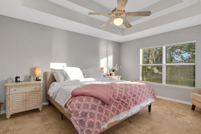 bedroom with ceiling fan, a tray ceiling, and multiple windows