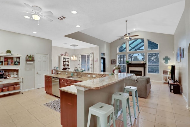 kitchen featuring a kitchen bar, sink, decorative light fixtures, light tile patterned floors, and a large island with sink