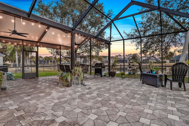 patio terrace at dusk with a lanai, grilling area, and ceiling fan