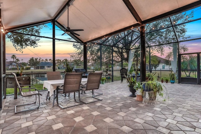 patio terrace at dusk featuring a lanai and ceiling fan