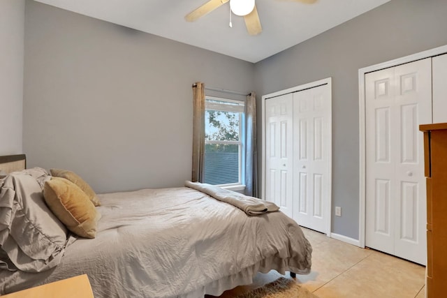 tiled bedroom featuring two closets and ceiling fan