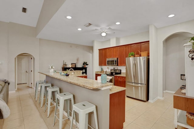 kitchen featuring ceiling fan, stainless steel appliances, a breakfast bar, and light tile patterned floors