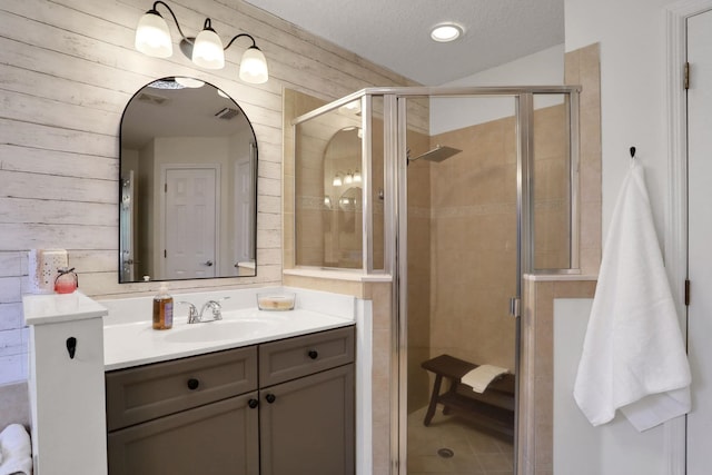 bathroom featuring vanity, a shower with shower door, wooden walls, and a textured ceiling