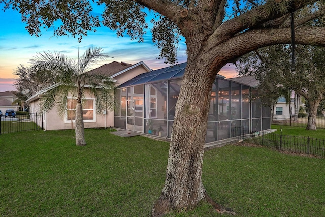 back house at dusk with a lanai and a yard