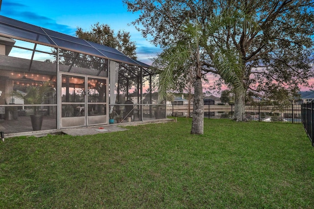 yard at dusk featuring a lanai