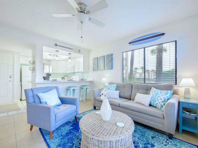 living area featuring ceiling fan, light tile patterned floors, and a textured ceiling