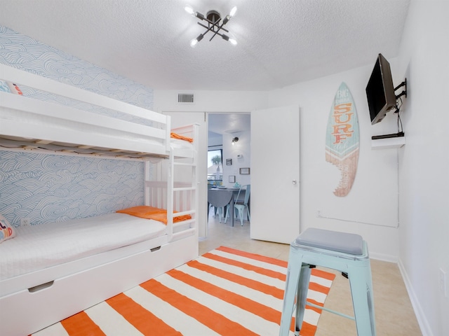 bedroom with visible vents, a textured ceiling, and baseboards