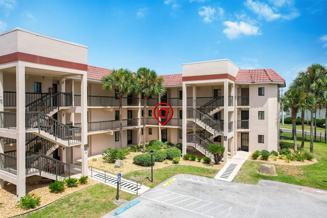 view of property featuring stairs and uncovered parking