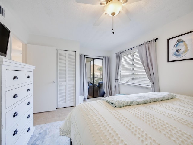 bedroom featuring light tile patterned floors, visible vents, ceiling fan, a closet, and a textured ceiling