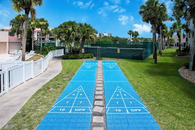 view of community featuring shuffleboard, a yard, and fence