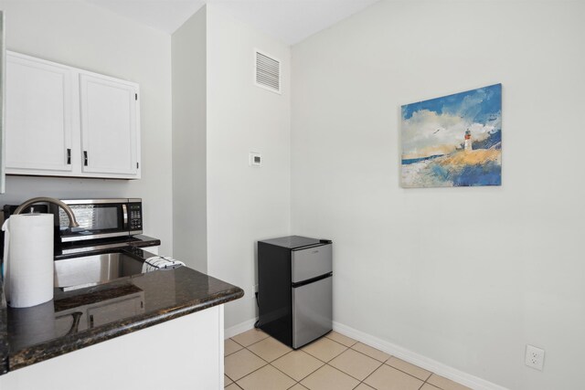 kitchen featuring visible vents, baseboards, light tile patterned flooring, white cabinets, and stainless steel appliances