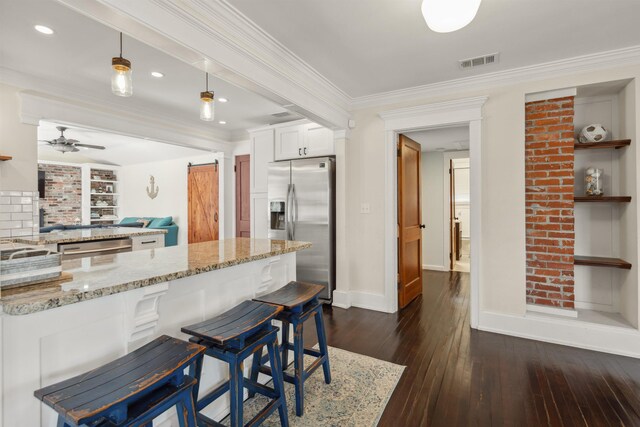 kitchen with a barn door, ornamental molding, visible vents, and stainless steel appliances