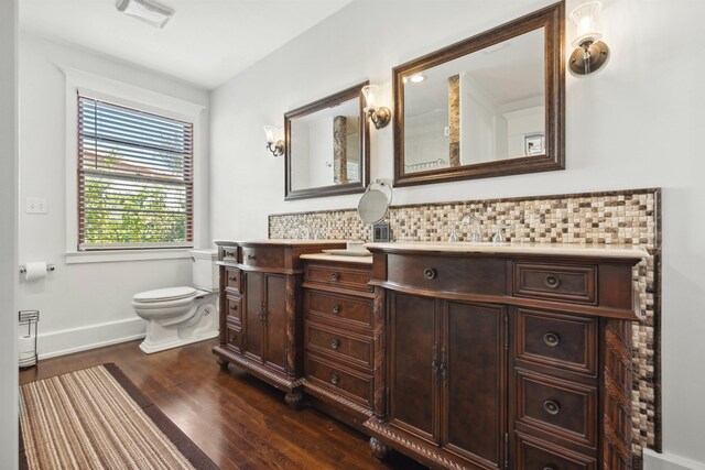 bathroom with toilet, tasteful backsplash, wood finished floors, baseboards, and vanity